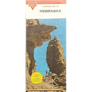 May include: A vintage Conoco Touraide map of Nebraska. The cover features a scenic illustration of rock formations under a blue sky, with two figures hiking. The map is prepared in cooperation with the Nebraska Game and Parks Commission.
