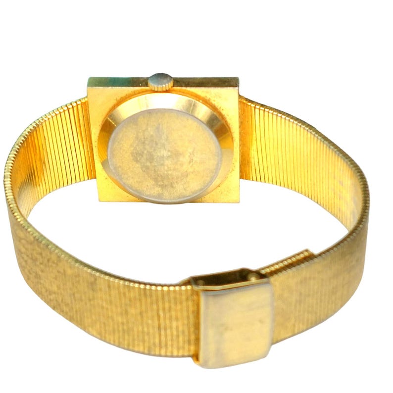 Puede incluir: Un reloj de pulsera dorado con una esfera cuadrada y una correa de malla dorada.