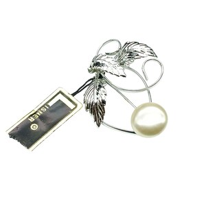 Puede incluir: Broche de plata con un diseño de perla y hojas. La broche tiene una etiqueta que dice "ISNER".