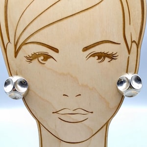 May include: A pair of silver earrings with a geometric design. The earrings are made of multiple circles that are connected together.