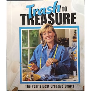 May include: A book cover with the title "Trash to Treasure" in blue and black lettering. The image features a woman in a denim shirt holding scissors and denim jeans. The text "The Year's Best Creative Crafts" is at the bottom.