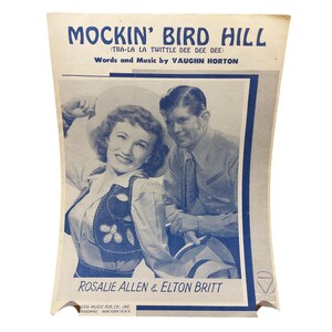 以下が含まれることがあります： ロザリー・アレンとエルトン・ブリットによる「Mockin' Bird Hill」の楽譜。表紙は青と白で、曲名が上に、アーティスト名が下にあります。Ern Music Pub. Co., Inc.発行。ヴィンテージスタイル。