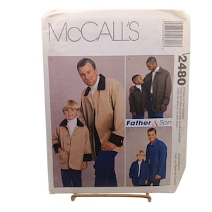May include: McCall's sewing pattern envelope featuring images of a father and son wearing matching jackets. The envelope has the number 2480 and the words "Father & Son" printed on it. The jackets are tan and navy blue.