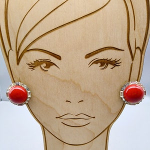 May include: A pair of red and gold clip-on earrings with a round red stone surrounded by clear rhinestones.