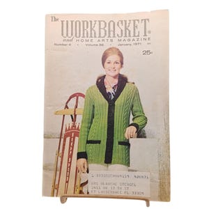 May include: The Workbasket and Home Arts Magazine, January 1971, features a woman wearing a green cardigan with black trim. The magazine cover also shows a vintage sled and the price of 25 pence.