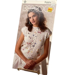 May include: A knitting pattern booklet titled Poppy by Berroco featuring a sleeveless white knit top with a central cable knit design and multicolored flecks throughout. The cover displays the text Poppy, Berroco, and Style 739 with a price tag.