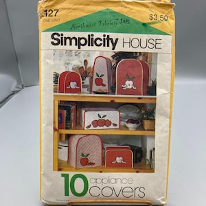 May include: A vintage Simplicity House pattern for 10 appliance covers. The covers feature red and white apple designs. The pattern packet is yellowed and includes the text "10 appliance covers".