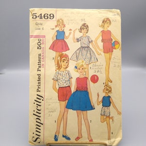 Könnte beinhalten: Vintage Simplicity Schnittmuster Nummer 5469 für ein Kinderkleid und eine Shorts. Das Muster umfasst fünf verschiedene Stile, mit Optionen für ein ärmelloses Kleid, ein Kleid mit kurzen Ärmeln und Shorts mit einem Oberteil. Das Muster ist auf vergilbtem Papier mit handschriftlichen Notizen gedruckt.