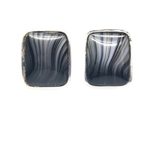 May include: A pair of silver earrings with black and white agate stone inserts. The stones have a wavy pattern.