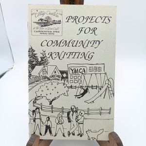 May include: A black and white illustration of a community with a daycare center, a YMCA, and a playground. The illustration is on a pamphlet titled "Projects for Community Knitting" with the text "Cottage Creations at the farm on Deer Creek, Carpenter, Iowa 50426-0070".