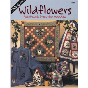 Puede incluir: Una colección de artículos hechos a mano con temática de flores silvestres. Incluye una camisa de mezclilla, edredones, cojines y una casita para pájaros, todos adornados con aplicaciones florales y de casitas. El texto "Wildflowers" y "Patchwork from the Meadow" son visibles.