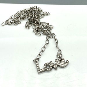 May include: A silver necklace with a pendant that says "LOVE" in silver with clear rhinestones.