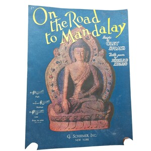 May include: Sheet music titled "On the Road to Mandalay" featuring a seated Buddha image. The text includes the names Oley Speaks and Rudyard Kipling. The background is a deep blue with musical notation and the publisher's name, G. Schirmer, Inc., New York.