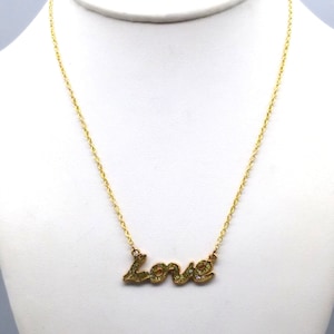 May include: Gold chain necklace with a sparkly gold 'love' pendant.