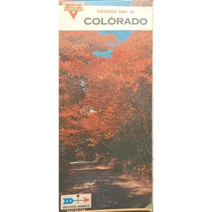 May include: Vintage Conoco Touraide map of Colorado. The cover features a scenic road lined with trees in autumn colors. The map has the Conoco logo and the text "Discover America Best By Car."