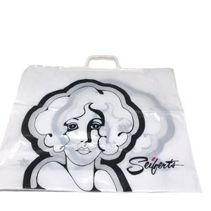 May include: White plastic shopping bag with a black and white illustration of a woman's face and the text "Seifert's" in black cursive.