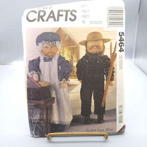 Op de afbeelding: Een vintage patroon-envelop met instructies voor het maken van oma- en opa-poppen. De poppen zijn afgebeeld in traditionele kleding: oma in een blauwe bloemenjurk en schort, opa in een overall en strohoed. De envelop heeft het woord "CRAFTS".