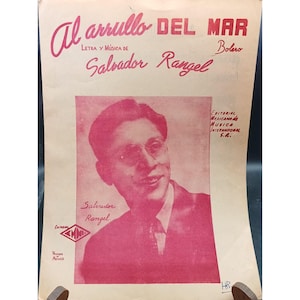May include: Sheet music cover with the title "Al arrullo DEL MAR" in red script. The cover features a portrait of Salvador Rangel in a red hue, with text indicating the song is a Bolero. The cover also includes the text "LETRA Y MÚSICA DE" and the name "Salvador Rangel".