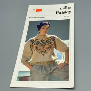 May include: A knitting pattern for a beige sweater with a colorful paisley design. The pattern is titled "DMC Paisley" and includes the number "15244". The pattern is for an "Embroider-a-Sweater".