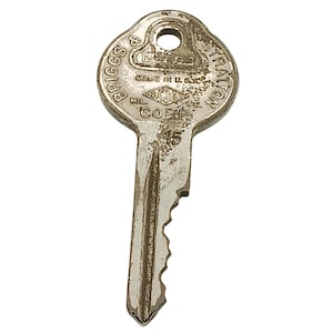 May include: Vintage metal key with the text "BRIGGS & STRATTON" and "MADE IN U.S.A." The key has a circular hole at the top and a jagged edge. The key is a silver color and shows signs of wear.