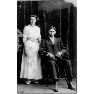 Cartão postal antigo RPPC em preto e branco com foto de um casal em traje formal, por volta do início dos anos 1900