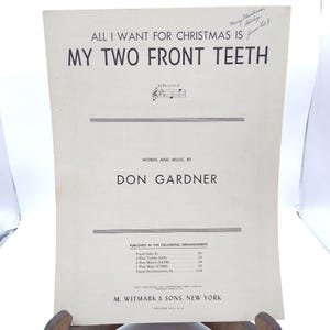 Puede incluir: Partitura de "All I Want for Christmas Is My Two Front Teeth" de Don Gardner. La partitura vintage tiene un fondo color crema con texto negro. El título está en letras grandes y en negrita. Hay texto escrito a mano en la esquina superior derecha.
