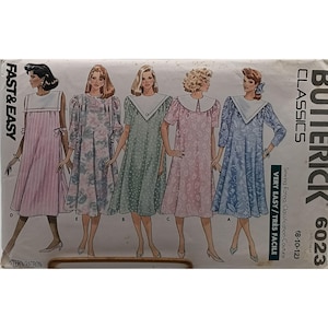 May include: Butterick Classics 6023 sewing pattern envelope featuring illustrations of five different dress variations. The dresses include various patterns like stripes, florals, and polka dots, all with wide collars. Text includes FAST & EASY.