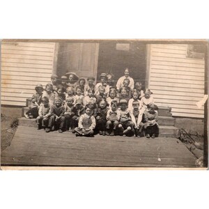 Cartão postal vintage com foto do grupo escolar RPPC do início dos anos 1900, crianças e professor em degraus em preto e branco