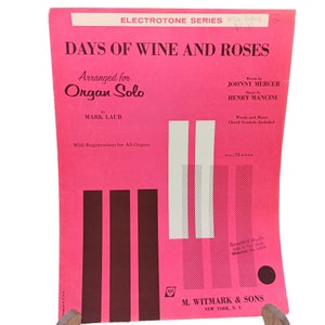 Puede incluir: Una portada de partitura rosa para la canción "Days of Wine and Roses" arreglada para órgano solo por Mark Laub. La portada presenta el título de la canción en letras grandes y negritas y el nombre del compositor en letras más pequeñas. La partitura es publicada por M. Witmark & Sons.
