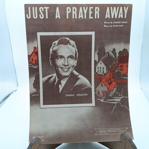 May include: A vintage sheet music cover for the song "Just a Prayer Away" featuring a black and white photo of Johnnie Johnston. The cover is brown with red and white accents.