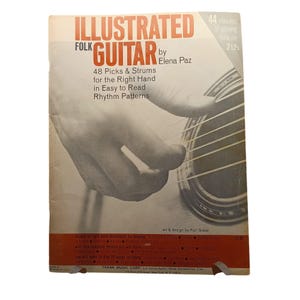 May include: An Illustrated Folk Guitar book by Elena Paz. The cover features a close-up of a hand strumming a guitar. The book promises 48 picks and strums for the right hand in easy-to-read rhythm patterns. The book also mentions 44 minutes of playing time on 2 LPs.