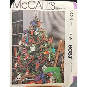May include: McCall's sewing pattern envelope featuring a decorated Christmas tree. The tree is adorned with colorful ornaments, red garland, and a star topper. The envelope includes the text "McCall's" and the pattern number 8087.