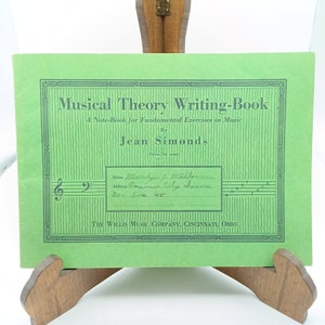 May include: A green cover for a music theory writing book by Jean Simonds. The cover has a title, author, and price. The cover also has a space for the student's name, address, and box number.