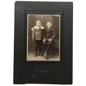 Fotografia vintage em preto e branco de dois meninos em moldura de papelão em relevo