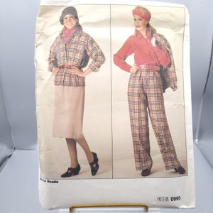 Op de afbeelding: Vintage naaipatroon met twee vrouwen in outfits. Eén draagt een geruite jas, rok en hoed. De ander draagt een rood overhemd, een geruite broek en een bijpassende hoed. Het patroonnummer is 0995.