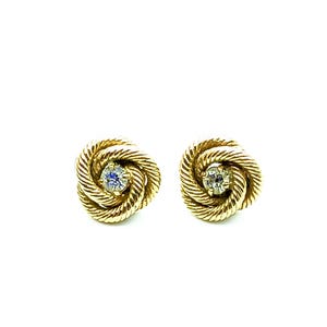 Peut inclure: Une paire de boucles d'oreilles dorées. Chaque boucle d'oreille présente un motif de corde torsadée entourant une petite pierre précieuse transparente. Les boucles d'oreilles sont posées sur un fond blanc.