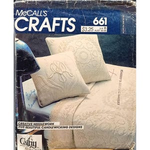 Op de afbeelding: Omslag van McCall's Crafts magazine met naaiwerkontwerpen. De afbeelding toont twee sierkussens en een sprei met candlewicking patronen. De tekst luidt "Creative Needlework, Five Beautiful Candlewicking Designs."