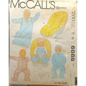May include: Vintage McCall's sewing pattern for baby clothes, with illustrations of a baby in a blue sleep sack, a yellow baby bouncer, and a pink and blue jumpsuit. The pattern is size 3 month.