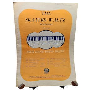 May include: Vintage sheet music for "The Skaters Waltz" by Waldteufel. The cover features a piano keyboard illustration with hands, set against an orange and cream background. The text includes "Four Hand Piano Duets" and a list of other musical pieces.
