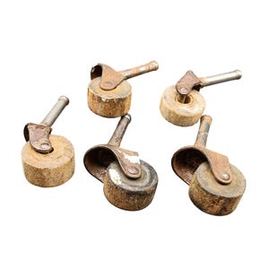May include: Five antique furniture casters with a rustic, weathered appearance. Each caster features a cylindrical wooden wheel, a metal bracket, and a metal stem. The metal components show signs of rust and age, adding to their vintage charm.