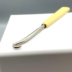 Peut inclure: Un crochet en plastique blanc avec un crochet en métal à l'extrémité. Le crochet mesure environ 15 cm de long.