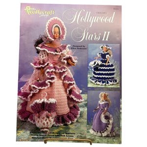 May include: A crochet pattern booklet titled Hollywood Stars II by The Needlecraft Shop featuring a doll in a pink and purple ruffled gown with a matching bonnet and umbrella, plus two smaller images of dolls in blue and purple crochet gowns.
