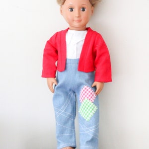 Könnte beinhalten: Eine Puppe, die einen roten Cardigan, eine blaue Jeans mit weißen Nähten und bunten Patchwork sowie ein weißes Hemd trägt.