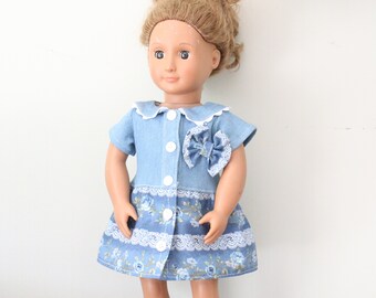 May include: A blue denim dress with a white collar and a floral print skirt. The dress has a bow on the front and white buttons.