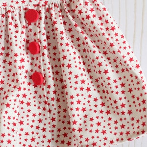 May include: A white skirt with a red star pattern and three red buttons.