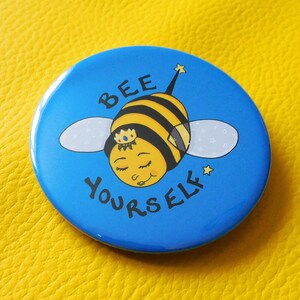 May include: A blue button featuring a cartoon bee wearing a crown and the text "BEE YOURSELF" in white.