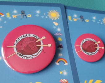 May include: Two pink round buttons with the text "Knitters with attitude" and a graphic of yarn and knitting needles. The buttons are on blue backgrounds with colorful illustrations.