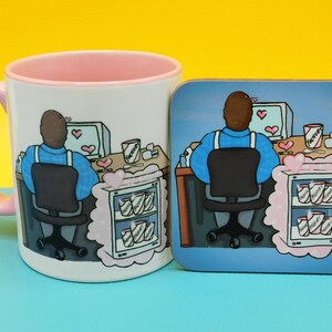 May include: A white ceramic mug with a pink rim features a cartoon illustration of a person sitting at a computer with hearts and a fridge filled with ice cream. The mug is next to a coaster with a similar illustration.