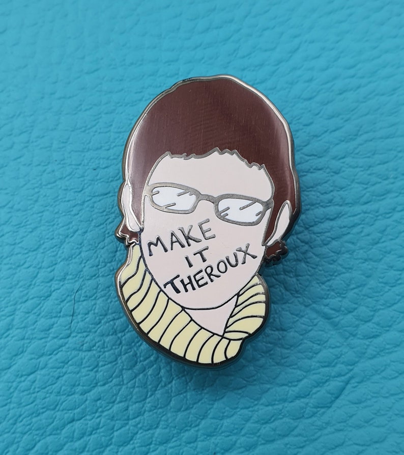 May include: A silver enamel pin featuring a cartoon illustration of a person with brown hair, glasses, and a yellow striped scarf. The text "MAKE IT THEROX" is written across the person's face.