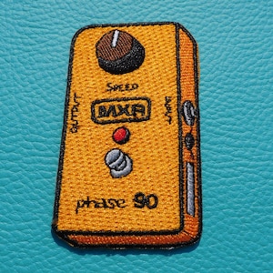 Peut inclure: Un patch de pédale de guitare MXR Phase 90 jaune. Le patch a des contours noirs et le texte "MXR", "phase 90" et "speed" en noir. Le patch a un bouton rouge et un bouton gris.